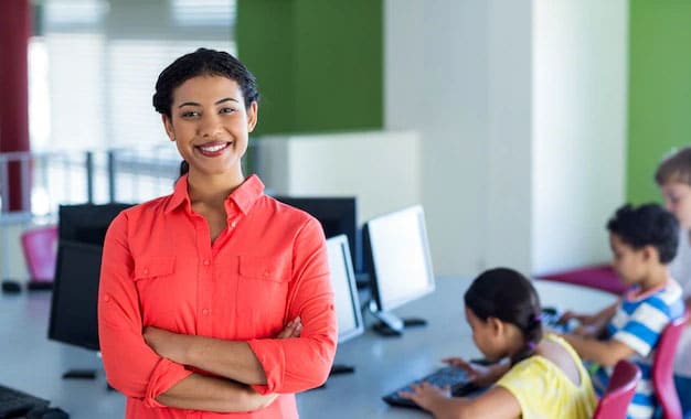confident-female-teacher-with-arms-crossed-standing-computer-room